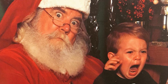 A freaked out Santa Claus and crying kid pose together to form an exceptionally awkward picture. 