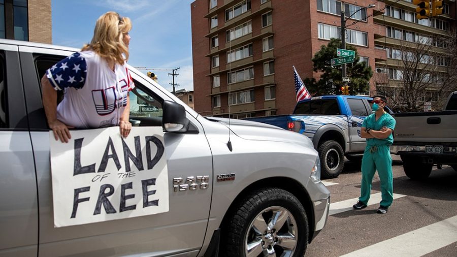 A man in scrubs blocks a protestor in Colorado. 
